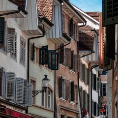 一位短发编辑手持笔记本站在窗前，城市夜景的玫红色霓虹倒映在玻璃上，正在记录要点
